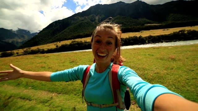 Cheerful-woman-takes-a-self-portrait-in-mountain-valley,