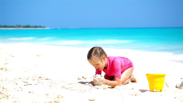 Adorable-little-girl-playing-with-beach-toys-on-white-sandy-beach