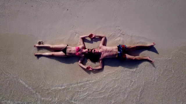 v03983-fliegenden-Drohne-Luftaufnahme-der-Malediven-weißen-Sandstrand-2-Personen-junges-Paar-Mann-Frau-romantische-Liebe-auf-sonnigen-tropischen-Inselparadies-mit-Aqua-blau-Himmel-Meer-Wasser-Ozean-4k