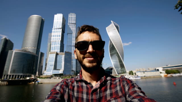 Hombre-de-turista-feliz-tomando-foto-selfie-usando-el-teléfono-inteligente-cerca-de-centro-internacional-de-negocios-en-Moscú