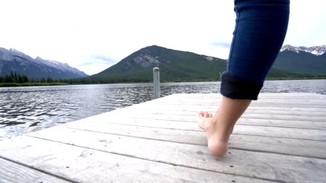 Pies-de-mujer-caminando-en-embarcadero-sobre-el-lago,-Canadá
