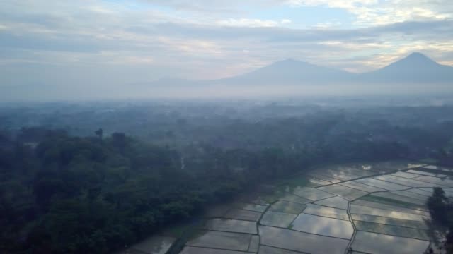 Aerial-view-drone-shot-of-Borobudur-town-in-Java-at-sunrise,-Indonesia-Travel-religion-drone-concept-4K-resolution-Rice-fields-and-volcano