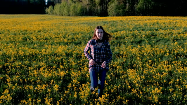 Happy-woman-brunette-runs-on-the-field-of-yellow-flowers.