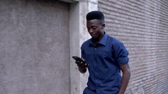 Attraktive-schwarze-afrikanische-Mann-zu-Fuß-und-auf-seinem-Smartphone-eingeben