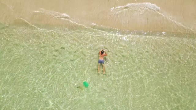 Man-swimming-in-crystal-clear-sea-water-drone-view-from-above.-Man-bathing-in-turquoise-sea-water-on-paradise-beach-aerial-view