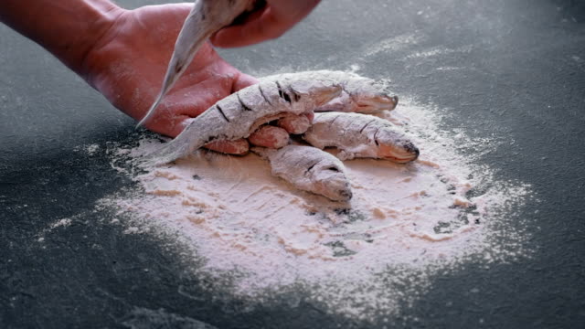 Man-takes-fish-in-flour-from-the-table-in-his-hand.-Cooking-fish.-Hands-close-up.
