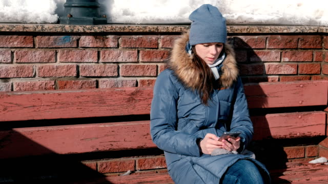 Mujer-es-viendo-páginas-de-internet-en-el-teléfono-móvil-en-Parque-de-invierno.