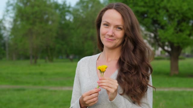 Woman-with-small-dandelions-in-hands-in-countryside
