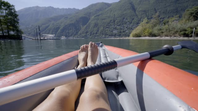 Personal-perspective-of-woman-on-red-canoe-paddling-on-beautiful-lake-in-summer-enjoying-outdoor-activities.-Point-of-view-of-person-canoeing-in-Switzerland.-4K-video