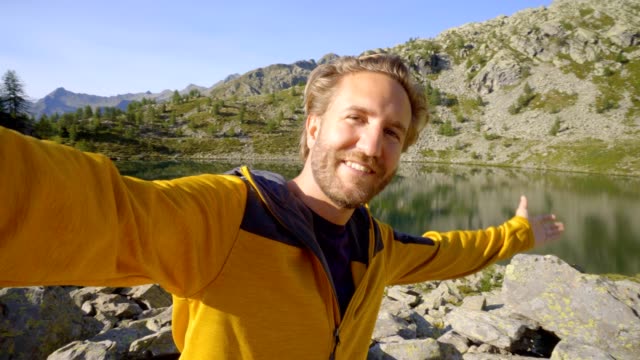 Junger-Mann-unter-Selfie-am-Bergsee.-Wanderland-Schweiz-Mann-nimmt-Selfies,-umgeben-von-einer-atemberaubenden-Berglandschaft.-Selfie-Reisen-Abenteuer-Lebensstil