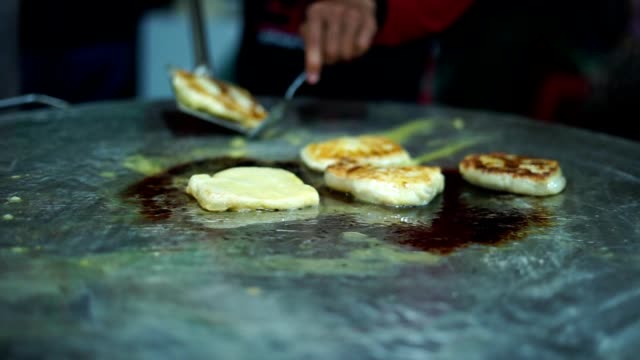 Vendedor-de-comida-callejera-haciendo-Roti-Canai-en-una-sartén