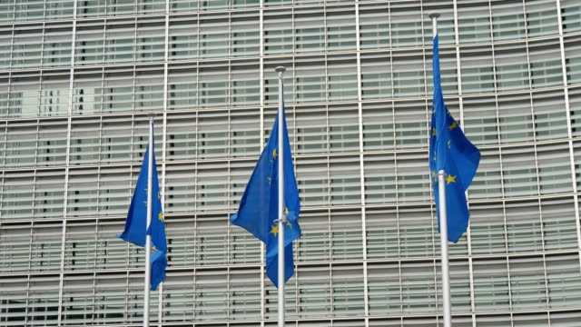 Erstaunlicher-Blick-auf-drei-EU-Flaggen-mit-gelben-Sternkreisen,-die-an-einem-sonnigen-Frühlingstag-im-EU-Büro-in-Brüssel-winken.
