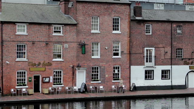 Menschen-am-traditionellen-Pub-am-Ufer-mit-Reflexionen-in-Canal
