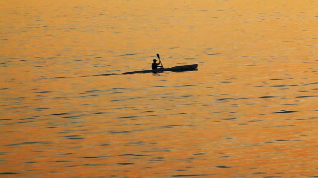 Mann-ein-Kajak-paddeln-Sie-in-den-Sonnenuntergang