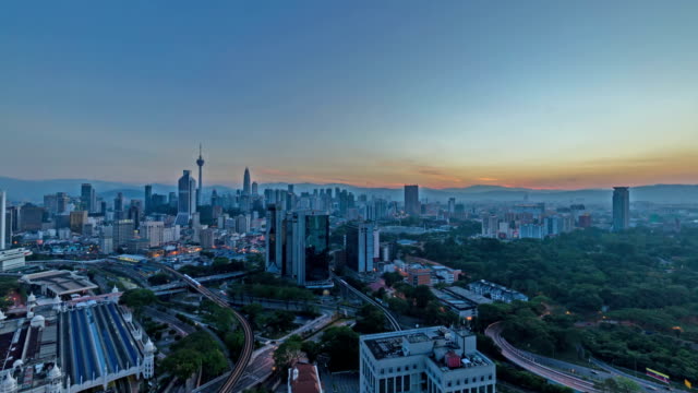 4k-footage-time-lapse-of-beautiful-sunrise-at-Kuala-Lumpur-city-centre-from-a-rooftop-of-a-building,-with-city-skyline,-train,-and-burst-sunlight.