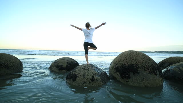 Weibliche-yoga-Übungen-auf-einem-boulder-by-die-Meer