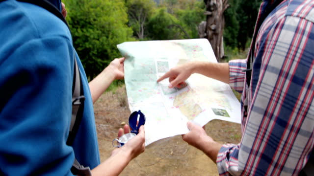 Vista-posterior-de-excursionistas-que-quieren-un-mapa-con-una-brújula