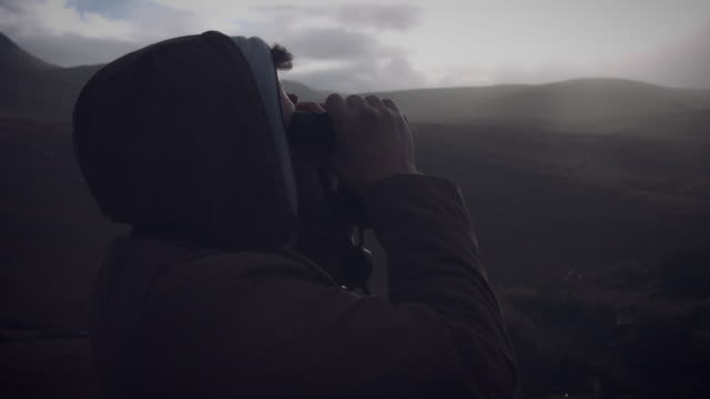 4k-Shot-of-A-man-with-binoculars-looking-on-Irish-village