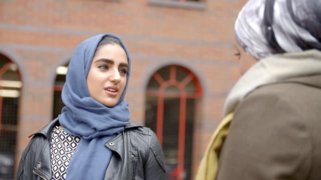 British-Muslim-Female-Friends-Meeting-In-Urban-Environment