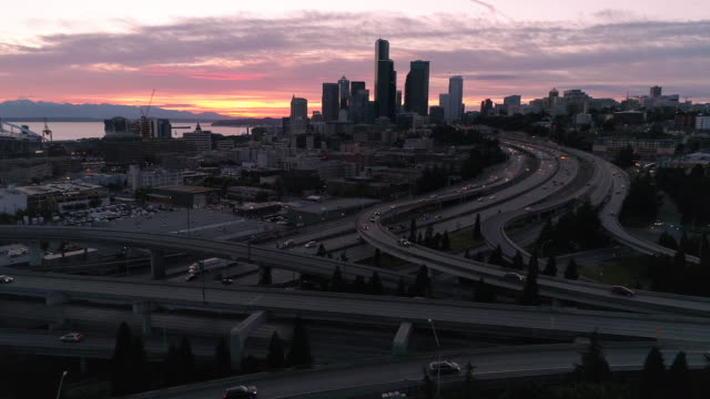 Roadtrip-Aerial-of-Cars-Traveling-from-City-on-Freeway-for-Night-Drive-with-Sunset-Afterglow