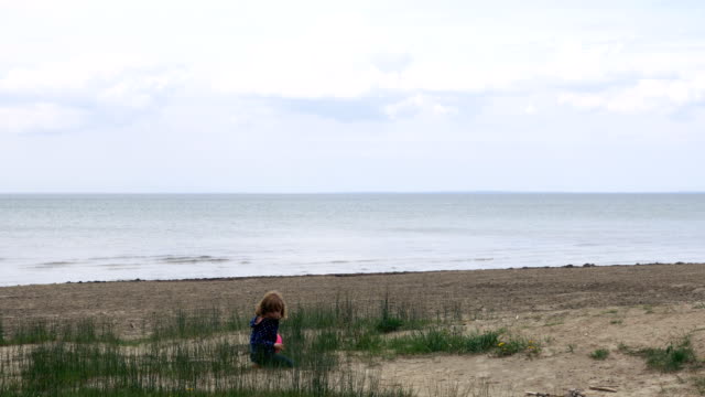 Kleine-Mädchen-spielen-im-Sand-des-Lake-Ontario-verläuft-in-Richtung-der-Kamera