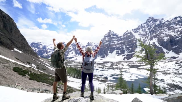 Happy-couple-arms-raised-foe-achievement-and-success-at-mountain-top