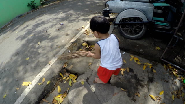 Two-year-old-boy-baby-sweeping-the-street-with-broomstick