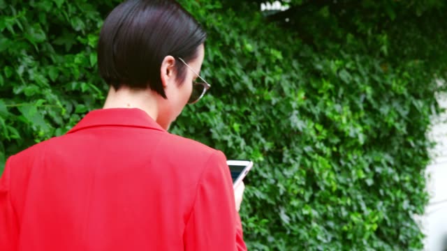 Stylish-Woman-Walking-Along-Urban-Street-Using-Mobile-Phone