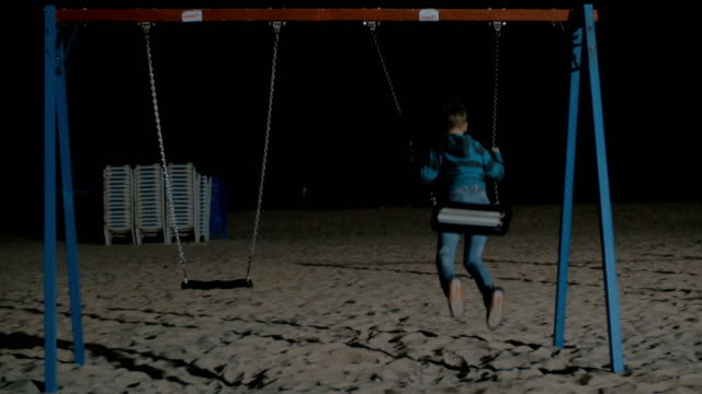 Kind-schwingt-allein-am-Strand-in-der-Nacht