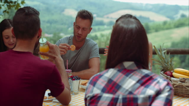 group-of-friends-doing-breakfast-outdoors-in-a-traditional-countryside.-shot-in-slow-motion