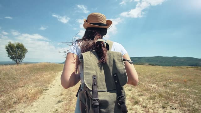 Female-European-traveler-with-backpack-on-the-trail-of-dried-field-at-trekking-lifestyle-trip