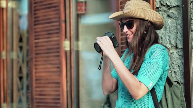 Junge-weibliche-Touristen-Fotografen-mit-Sonnenbrille-und-Hut-nehmen-Foto-mit-professioneller-Kamera