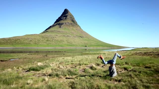 Drone-point-of-view-of-Young-woman-exercising-yoga-headstand-pose-in-pure-nature,-Iceland.-People-travel-healthy-lifestyle-and-yoga-concept--4K-video