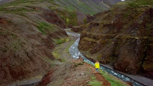 Amazing-drone-point-of-view-of-woman-hiking-on-mountain-ridge-over-canyon-in-Iceland