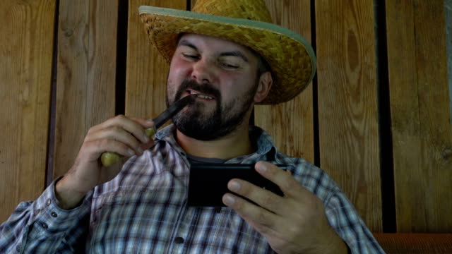 A-man-in-a-hat-and-a-knife-looks-at-the-smartphone