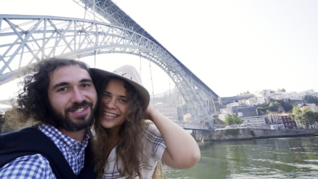 Couple-taking-funny-selfie-on-embankment-near-bridge
