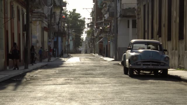 Tourists-couple-walk-on-rustic-street-in-old-Havana-during-golden-hour-light