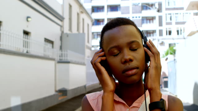 Woman-listening-music-on-headphones-while-walking-in-city-street-4k