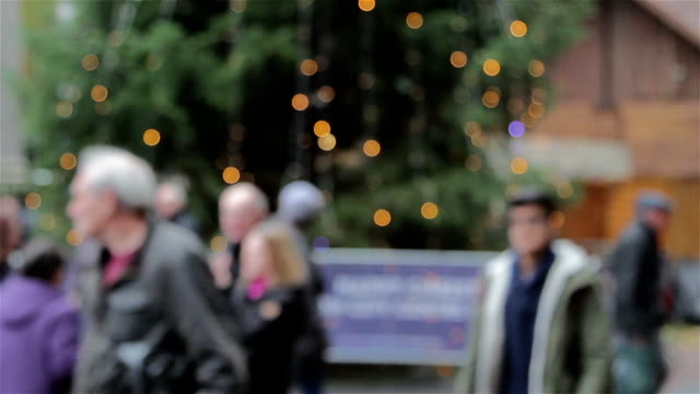 Large-Anonymous-Crowd-Walk-Past-Out-of-Focus-Xmas-Tree-Lights