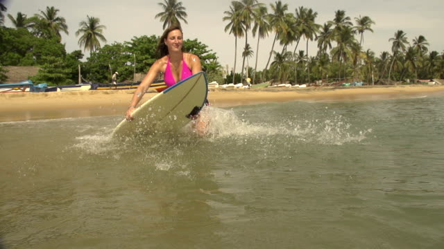 Weibliche-surfer-Sprünge-auf-dem-Surfbrett-und-beginnt-Paddeln