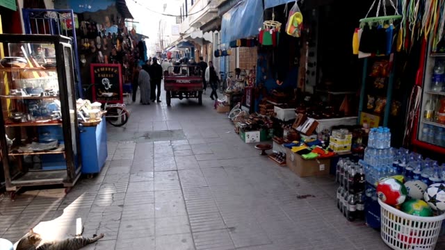 People-walking-and-a-carriage-going-on-a-relatively-narrow-pedestrian-street-in-Essouira