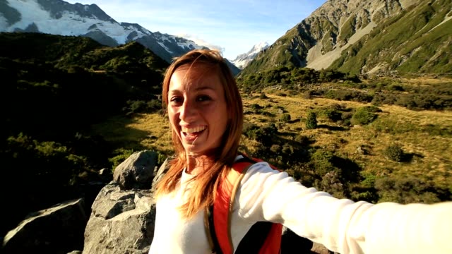 Young-woman-takes-self-portrait-on-mountain-background