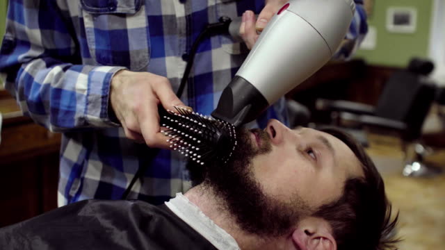 Barber-is-drying-beard-a-bearded-man-with-hairdryer-in-a-barber-shop