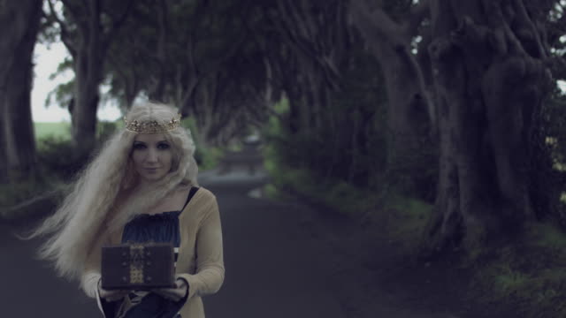 4k-Fantasy-Shot-in-Dark-Hedges,-Queen-Holding-and-Showing-a-Box