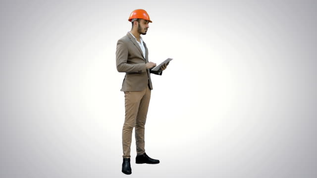 Engineer-in-helmet-carrying-out-inspection-using-tablet-on-white-background