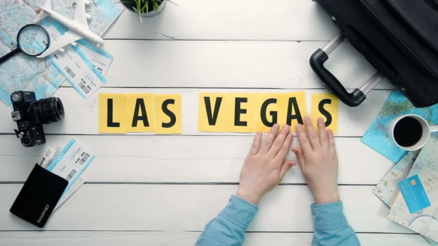 Top-view-time-lapse-hands-laying-on-white-desk-word-"LAS-VEGAS"-decorated-with-travel-items