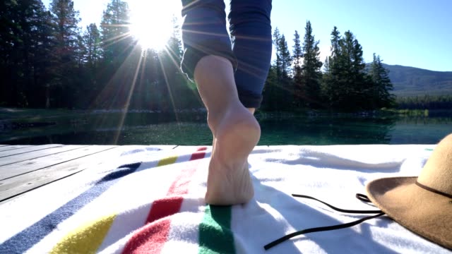 Geschlossen-bis-auf-Frau-die-Füße,-zu-Fuß-auf-einem-Holzsteg-über-atemberaubende-Seenlandschaft-im-Herzen-der-kanadischen-Rocky-Mountains