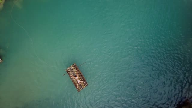Drone-shot-aerial-view-of-young-woman-lying-down-like-star-shape-on-bamboo-rafting-at-tropical-waterfall.-4K-resolution-video,-shot-in-the-Philippines.-People-travel-fun-vacations-adventure-concept