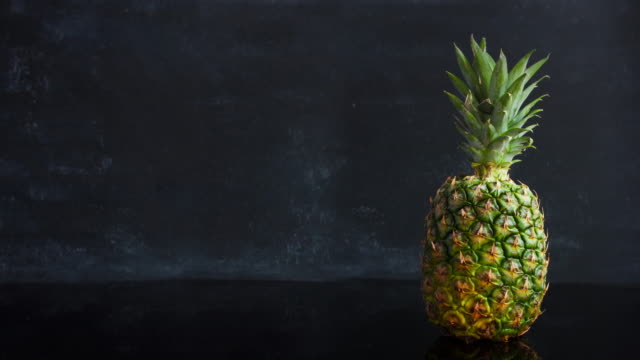 Stop-motion-ripe-tropical-fruit-pineapple-on-a-black-background.-Time-lapse-food-footage