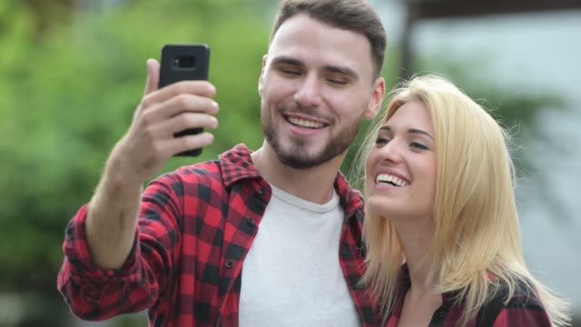Young-happy-couple-taking-selfie-together-in-the-streets-outdoors